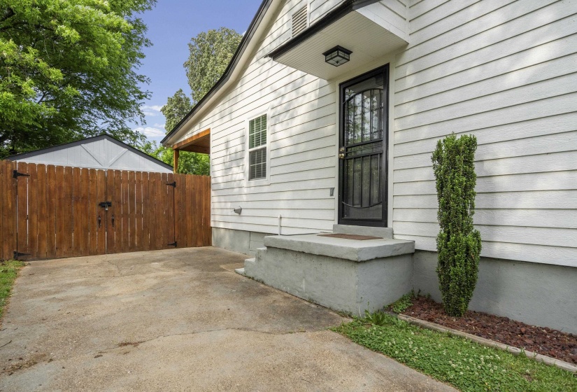 White horizontal siding exterior with a black security door and concrete steps