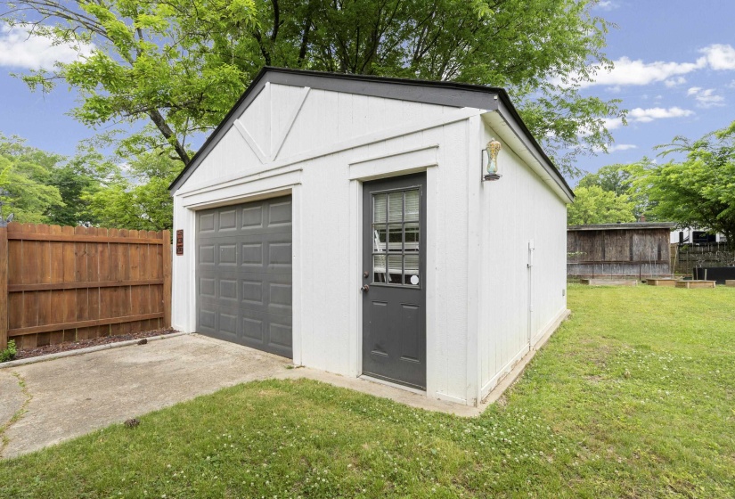 Detached outbuilding with a single garage bay, separate entry door, and exterior lighting fixture