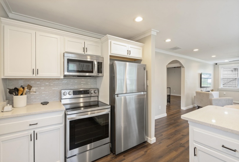 Kitchen featuring white cabinetry with dark hardware, a mosaic tile backsplash, stainless steel appliances, and light-toned countertops