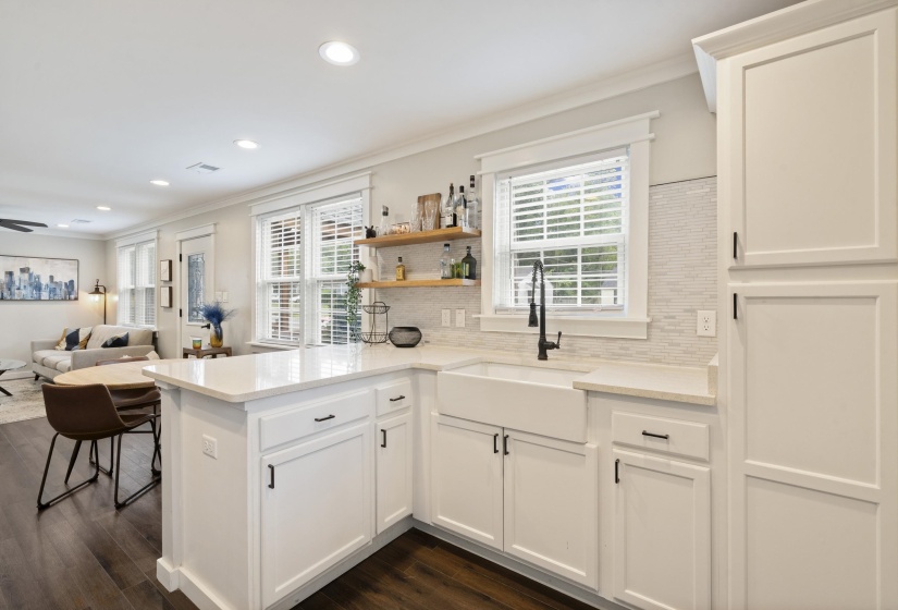 Modern kitchen featuring white shaker-style cabinetry, a white farmhouse sink with a matte black faucet, and light-toned countertops