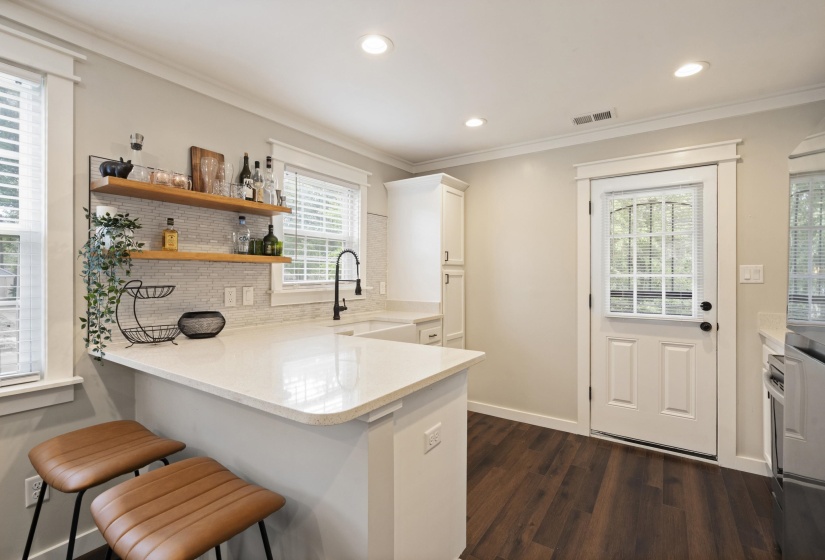 Kitchen featuring wood-finish flooring, recessed lighting, and a white paneled door with integrated blinds