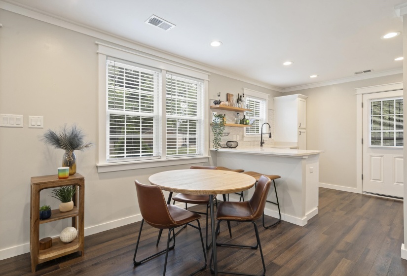 Open-concept living space featuring wood-finish flooring, recessed lighting, and crown molding