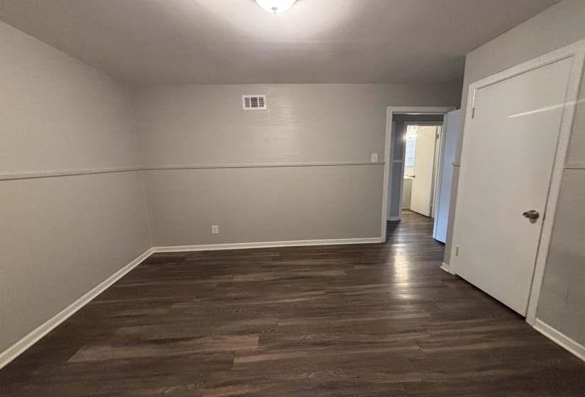 Spacious room featuring wood-finish flooring, light grey walls, and white trim