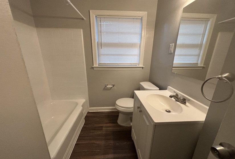 Bathroom featuring a white vanity with integrated sink, chrome faucet, and wood-finish flooring