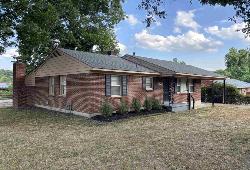 Brick exterior featuring a covered porch entry, carport, and architectural shingle roof