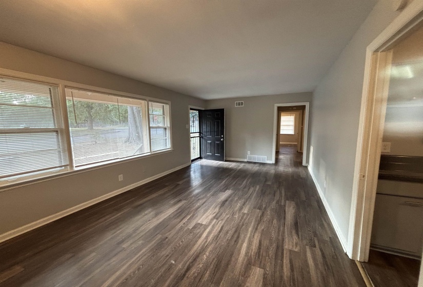 Spacious room featuring wood-finish flooring, light gray wall paint, and white baseboards