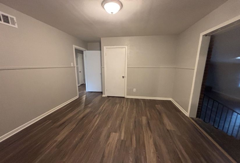 Room featuring wood-finish flooring, two-tone painted walls, white baseboards, and a flush-mount ceiling light