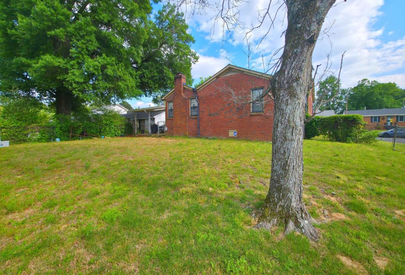 Spacious rear yard with a red brick exterior residence featuring a chimney