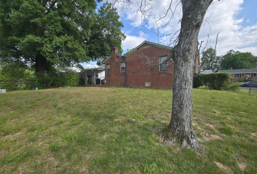 Expansive grassy lawn with established perimeter fencing and mature trees