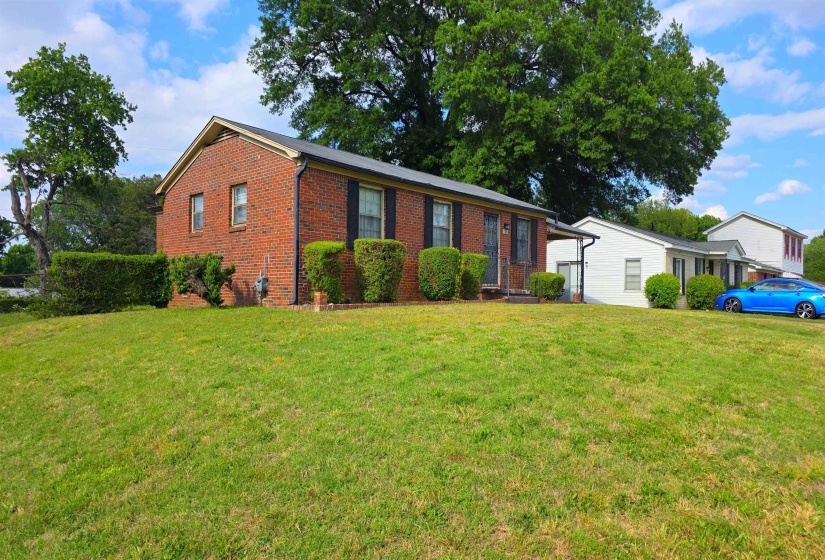 Brick ranch-style residence featuring a prominent front lawn
