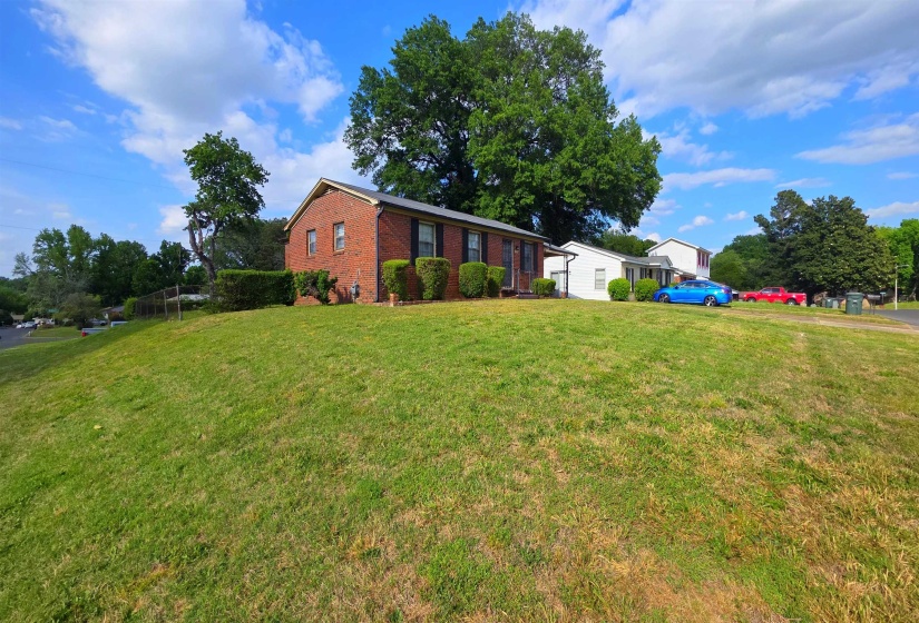 Brick exterior residence featuring a front lawn with mature landscaping