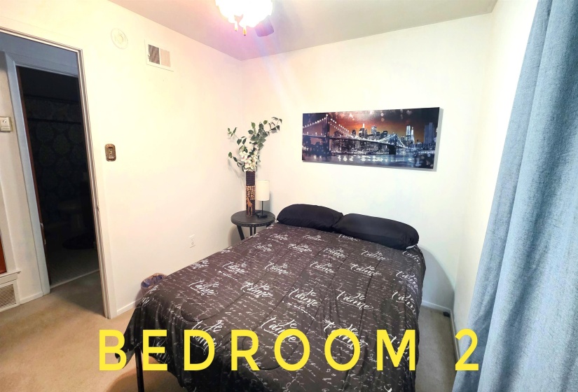 Carpeted bedroom featuring neutral wall tones, a ceiling light fixture, and an open doorway