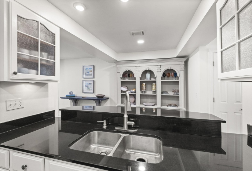 Kitchen area featuring black countertops with a double basin stainless steel sink and a gooseneck faucet