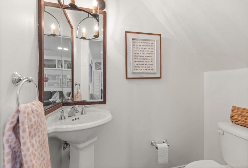 Pedestal sink with chrome fixtures and a medicine cabinet featuring an arched light fixture