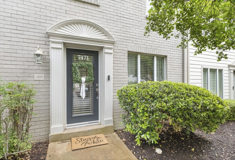 Brick facade entry featuring a glass-paneled door with decorative pilasters and an arched pediment