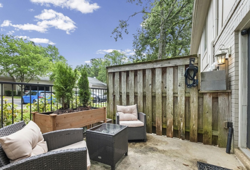 Private patio space with a concrete slab, wooden privacy fence, and a large wood planter box