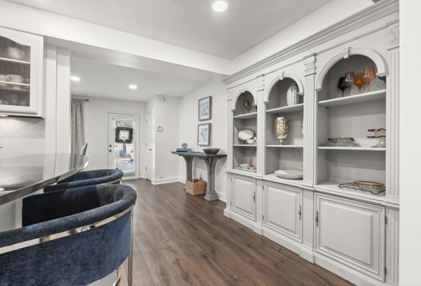 Built-in shelving unit with arched details and lower cabinetry, complemented by wood-finish flooring and recessed lighting