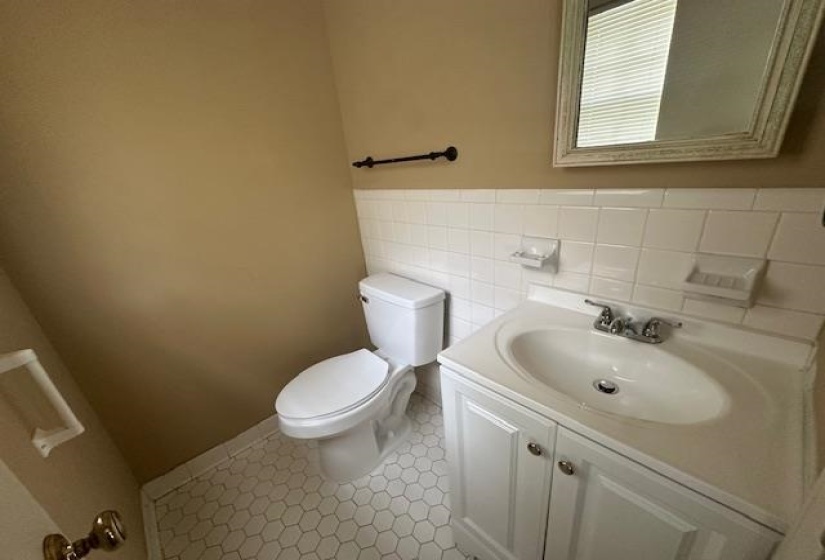 Bathroom featuring a white vanity with integrated sink, chrome faucet, and white hexagon tile flooring