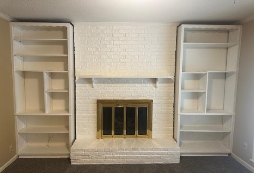 White-painted brick fireplace with a brass firebox and a decorative mantel