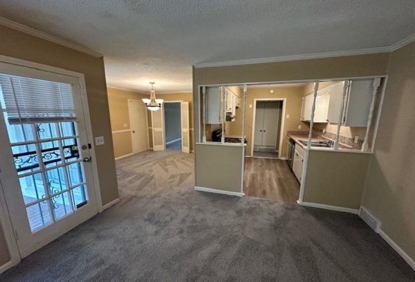 Living area featuring grey patterned carpeting, a white French door with decorative ironwork, and crown molding