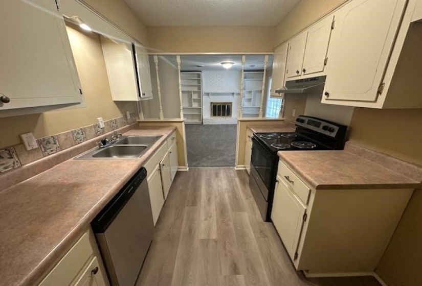 Galley kitchen featuring wood-finish flooring, light-toned countertops, and painted cabinetry