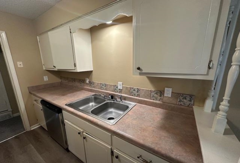 Kitchen sink area featuring a double basin stainless steel sink, laminate countertops, and a decorative tile backsplash