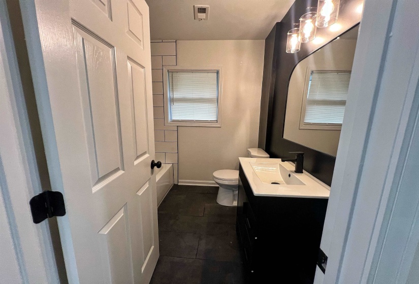 Full bath featuring vanity and dark tile patterned flooring