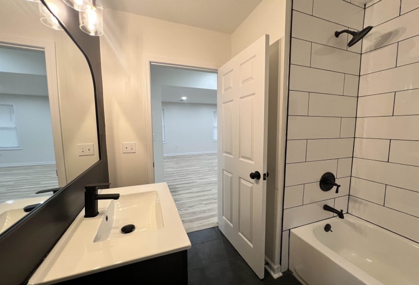 Full bath with vanity, shower / bath combination, and dark tile patterned flooring