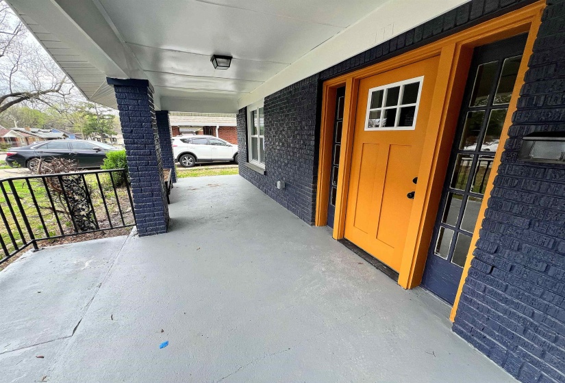 Property entrance featuring covered porch and brick siding