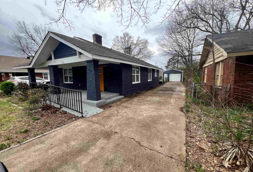 View of property exterior featuring a chimney, a garage, an outbuilding, brick siding, and a porch