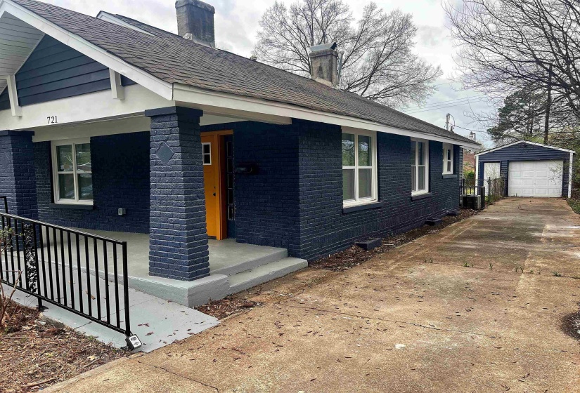 View of home's exterior featuring a chimney, brick siding, a detached garage, an outdoor structure, and concrete driveway