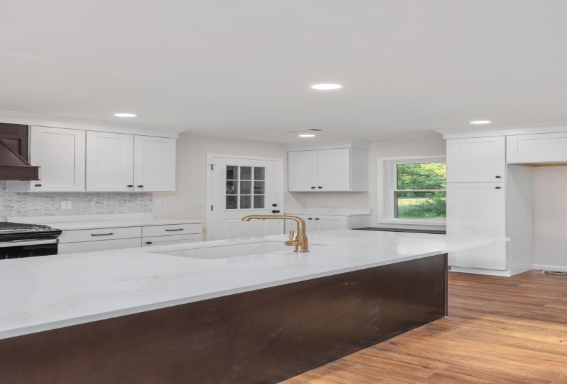 Kitchen with light stone counters, white cabinetry, recessed lighting, light wood-style floors, and stainless steel gas range oven