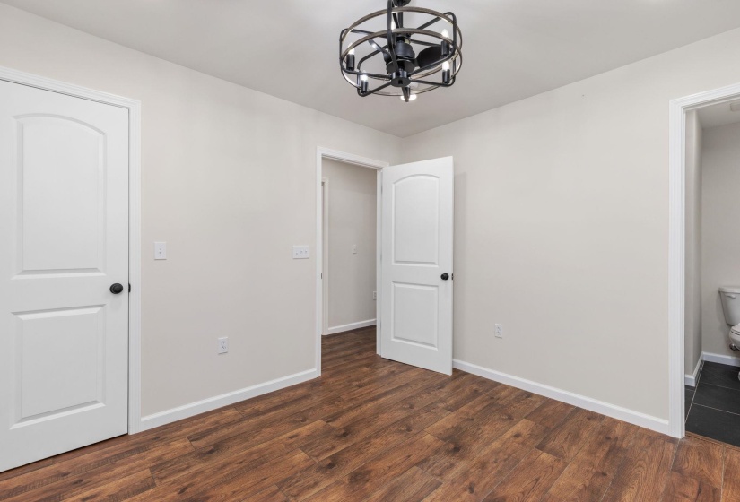 Unfurnished bedroom featuring a chandelier and dark wood-style flooring