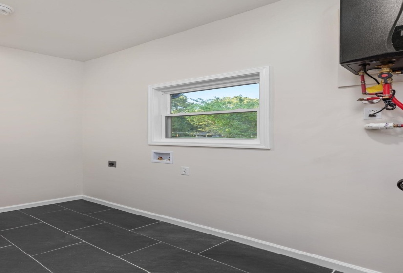Laundry area with electric dryer hookup, dark tile patterned flooring, and hookup for a washing machine