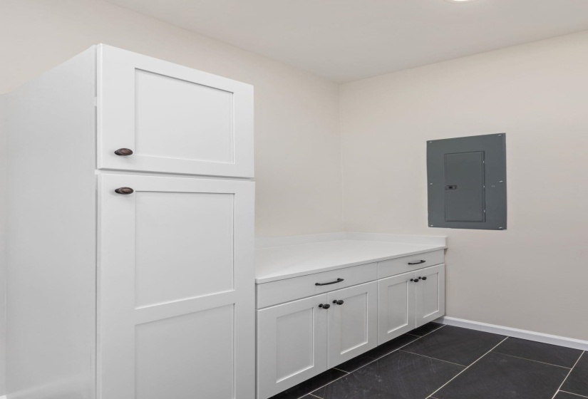 Mudroom with electric panel and dark tile patterned flooring