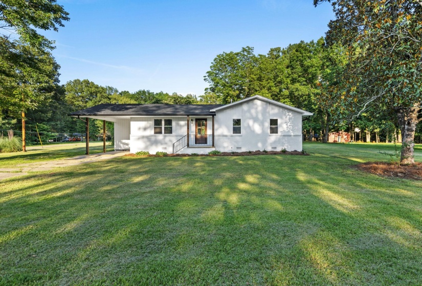 View of front of home with a front lawn, a carport, and crawl space
