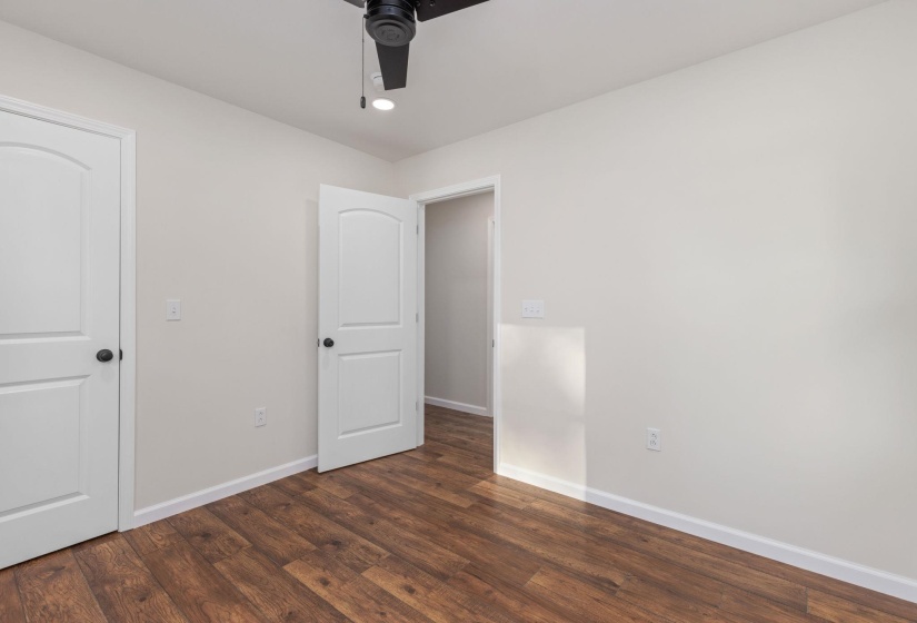 Unfurnished bedroom with dark wood-style floors and a ceiling fan