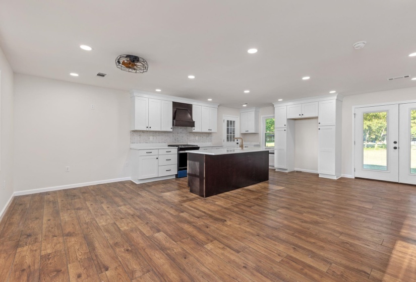 Kitchen with gas range, custom range hood, healthy amount of natural light, dark wood-style flooring, and recessed lighting
