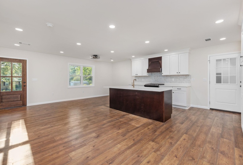 Kitchen featuring light countertops, wood finished floors, custom exhaust hood, white cabinets, and recessed lighting