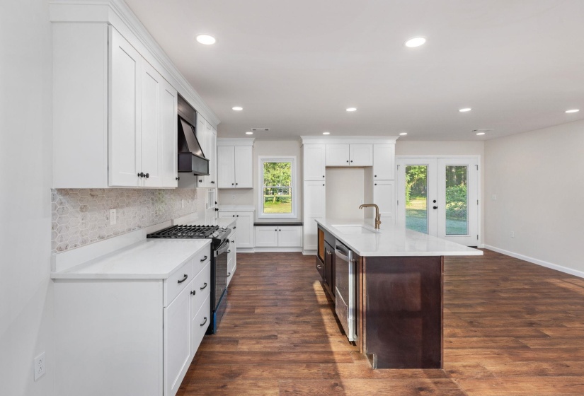 Kitchen featuring gas range, wall chimney range hood, backsplash, recessed lighting, and light countertops