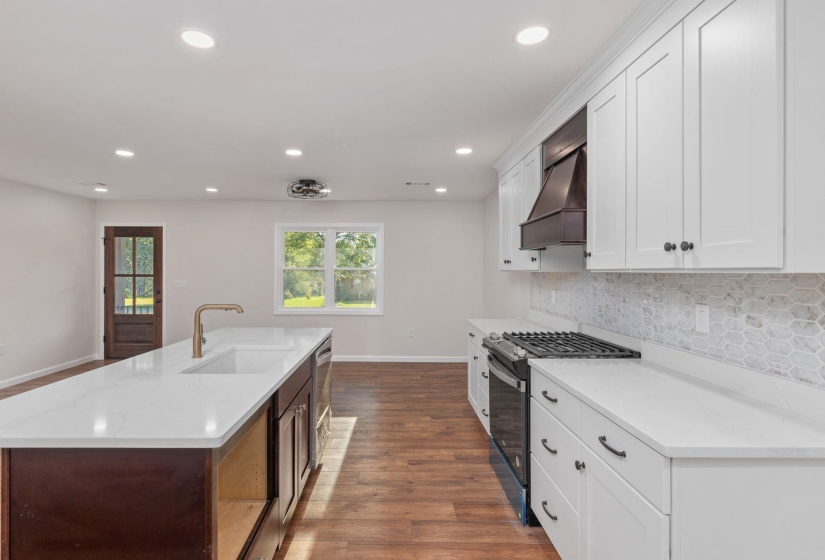 Kitchen featuring gas range, custom range hood, backsplash, recessed lighting, and dark wood-type flooring