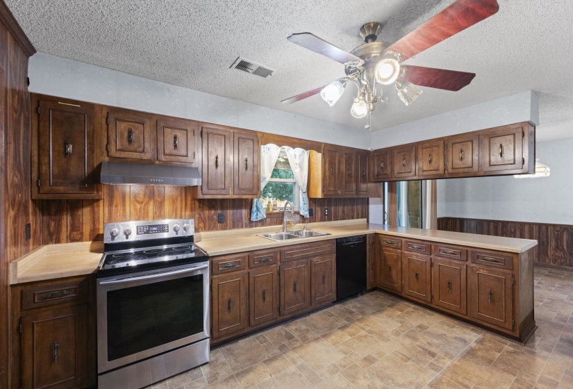 Kitchen featuring wood-panel walls, wood-finish cabinetry, and laminate countertops