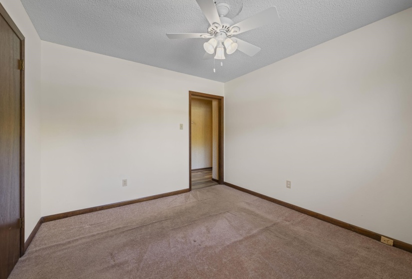 Room with a ceiling fan, light-colored walls, wood-trim baseboards, and carpet flooring