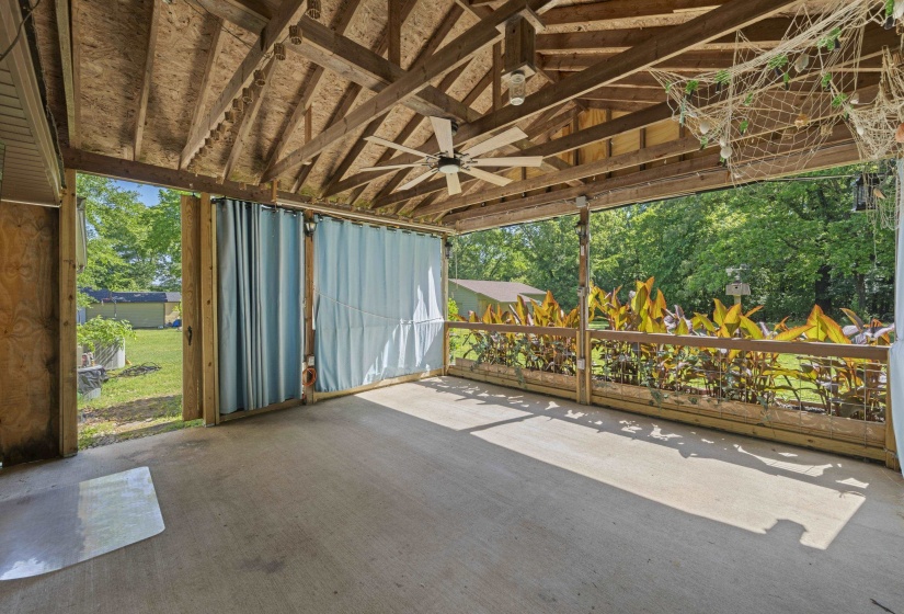 Spacious covered patio with concrete flooring and exposed wood beam ceiling