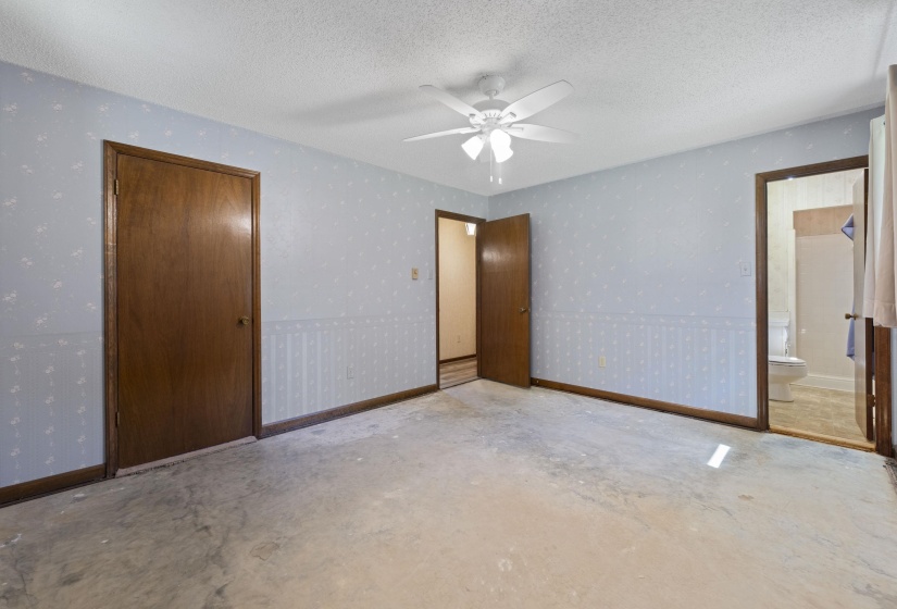 Room with light blue patterned wallpaper, dark wood trim, and a white ceiling fan with integrated lighting