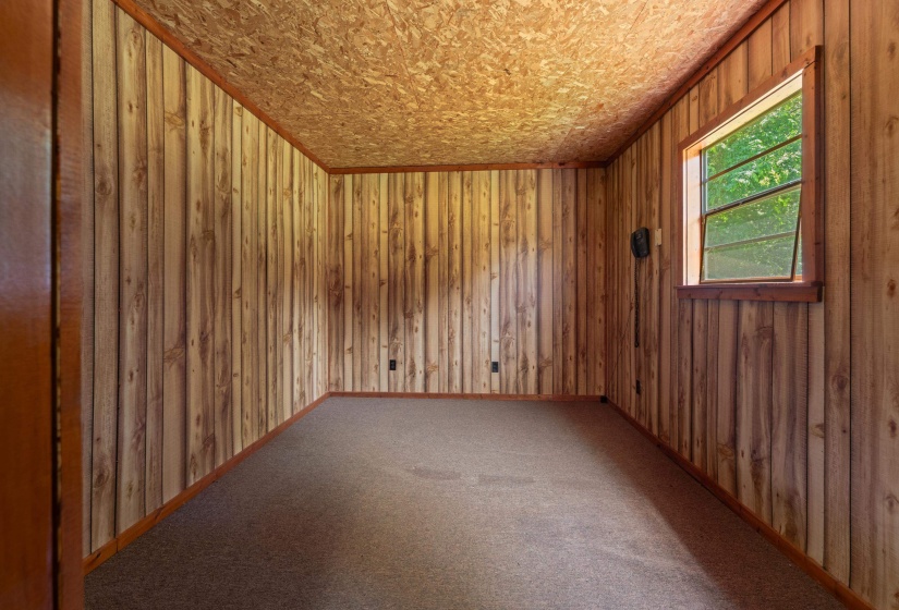 Interior room with wood-panel walls, coordinated wood trim, and a window providing natural light