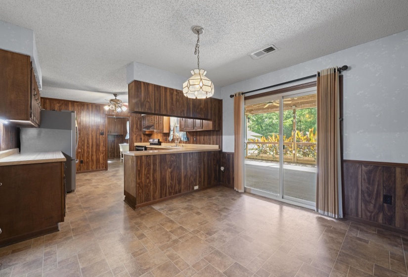 Open-concept kitchen and dining area featuring wood-finish paneling and cabinetry