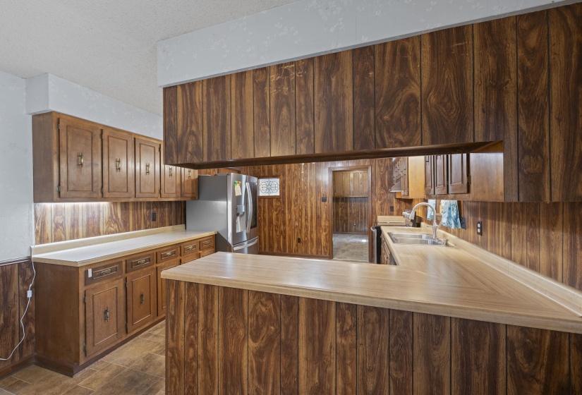 Kitchen featuring wood-panel walls, wood-finish cabinetry, and light-toned countertops