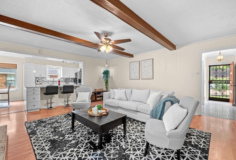 Living area featuring exposed ceiling beams, a ceiling fan, and wood-finish flooring