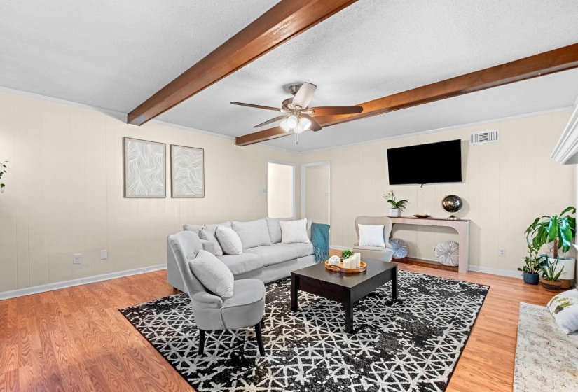 Living area featuring wood-finish flooring, exposed ceiling beams, and a ceiling fan